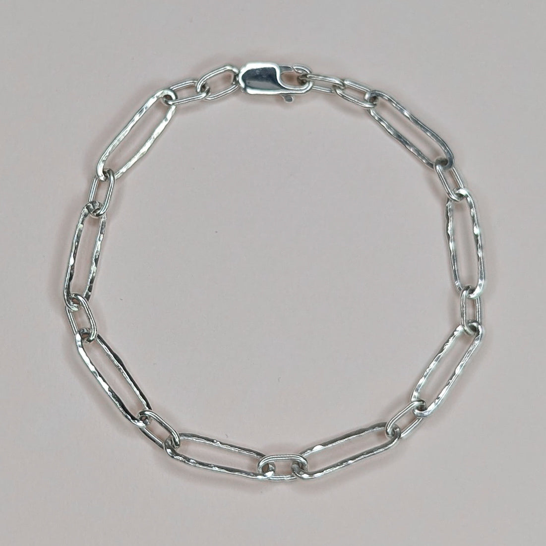 Silver chain bracelet on a light pink background