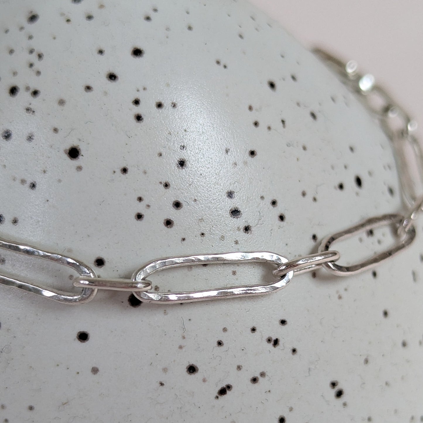 Silver chain necklace on a speckled surface