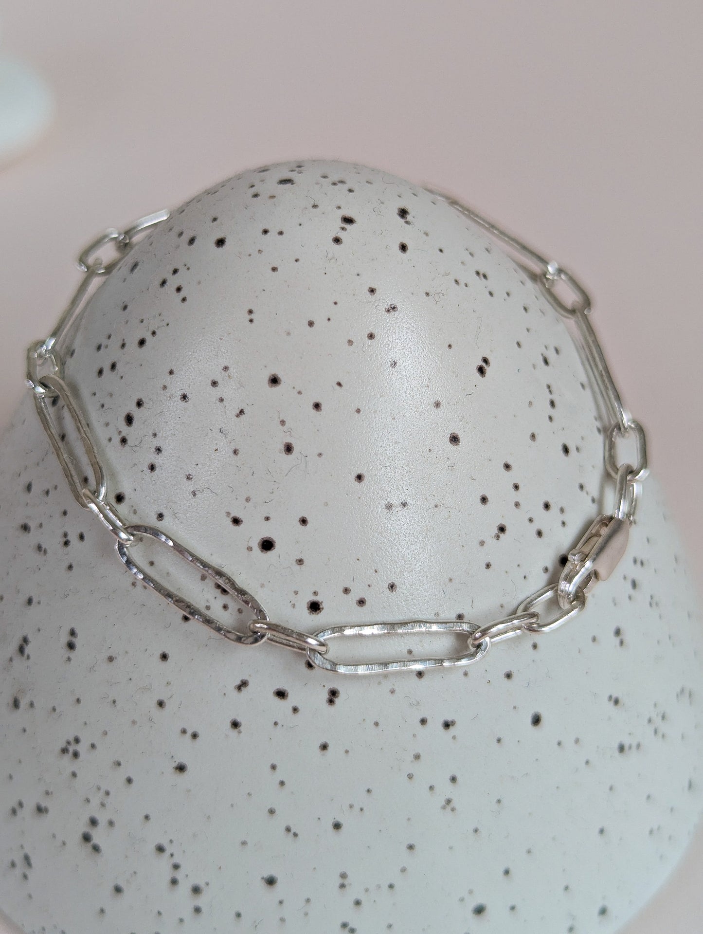 Silver chain bracelet on a speckled ceramic surface