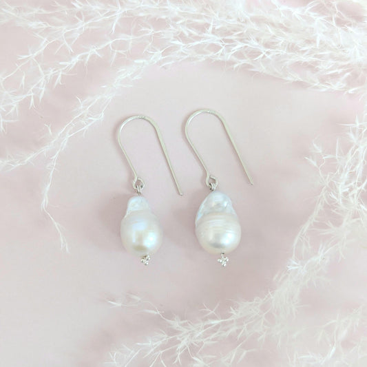 Handcrafted 925 sterling silver genuine large Baroque pearl drop earrings worn on a modern arched sterling silver ear wire