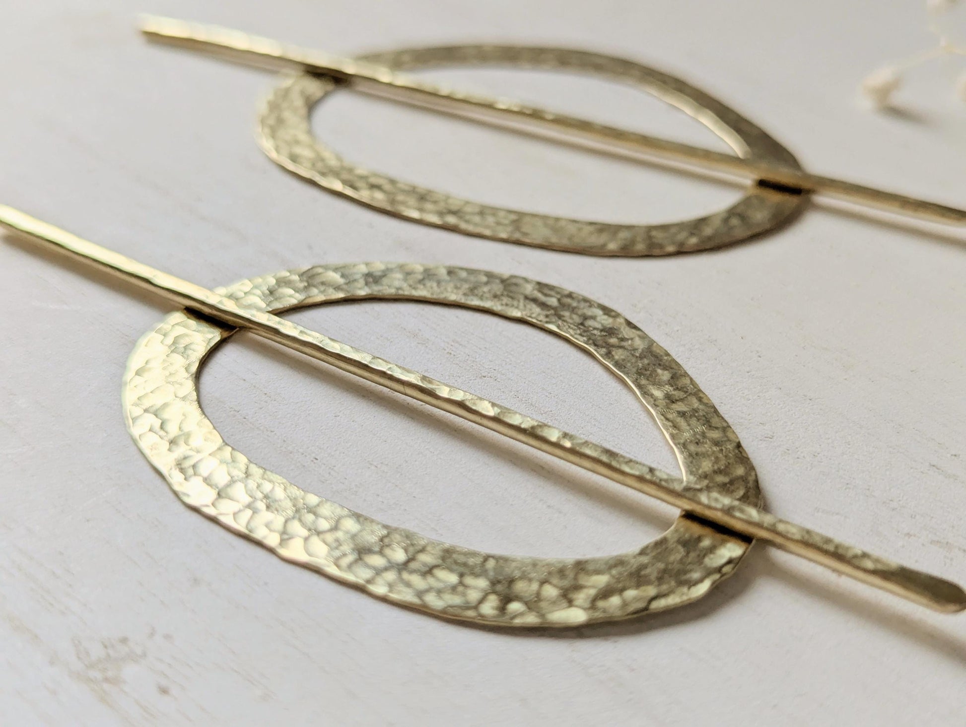 Pebble gold hammered brass round hair stick barrette bun holder - close up of the hammered texture on the pin and pebble shaped barrette