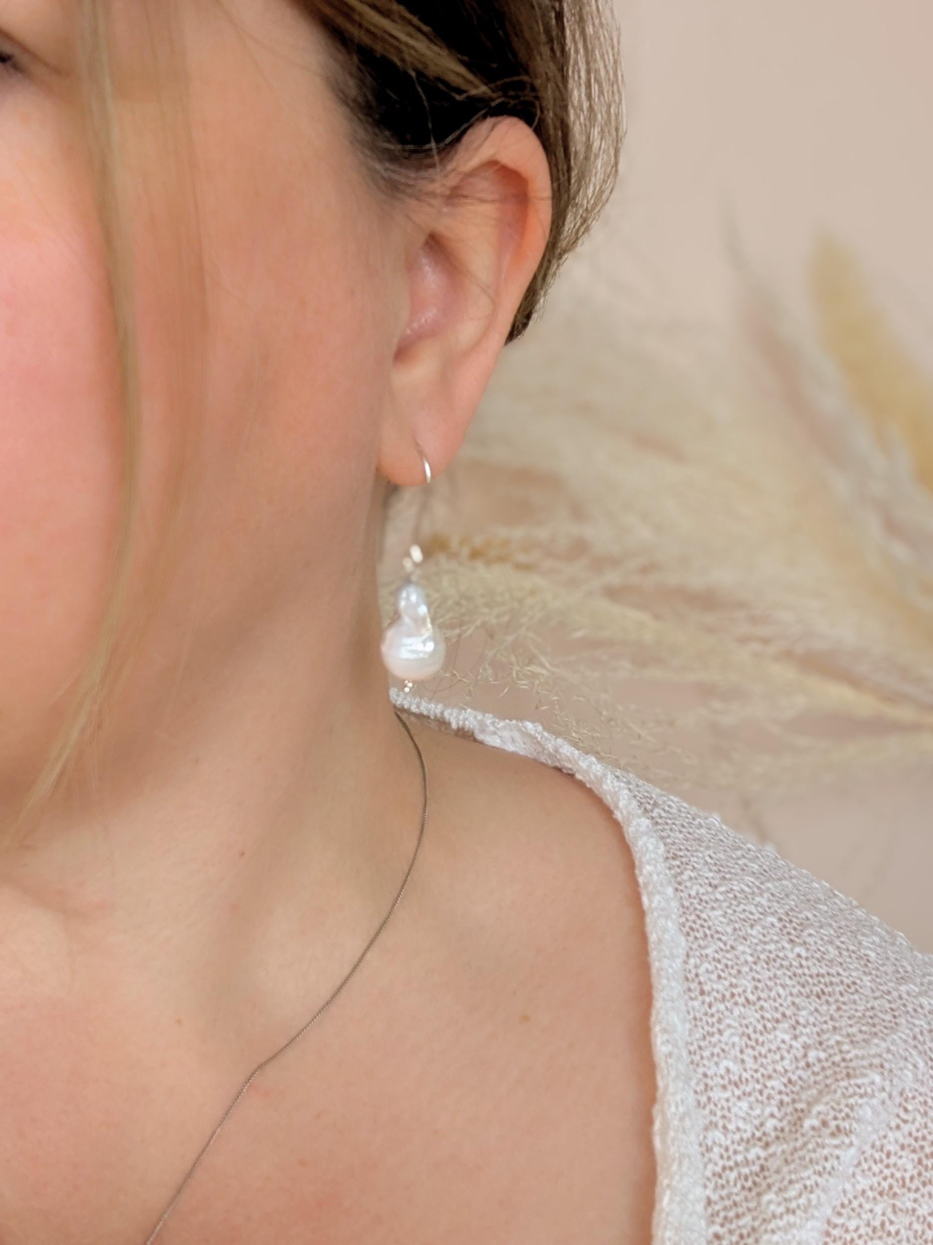 Handcrafted 925 sterling silver genuine large Baroque pearl drop earrings worn on a modern arched sterling silver ear wire shown worn