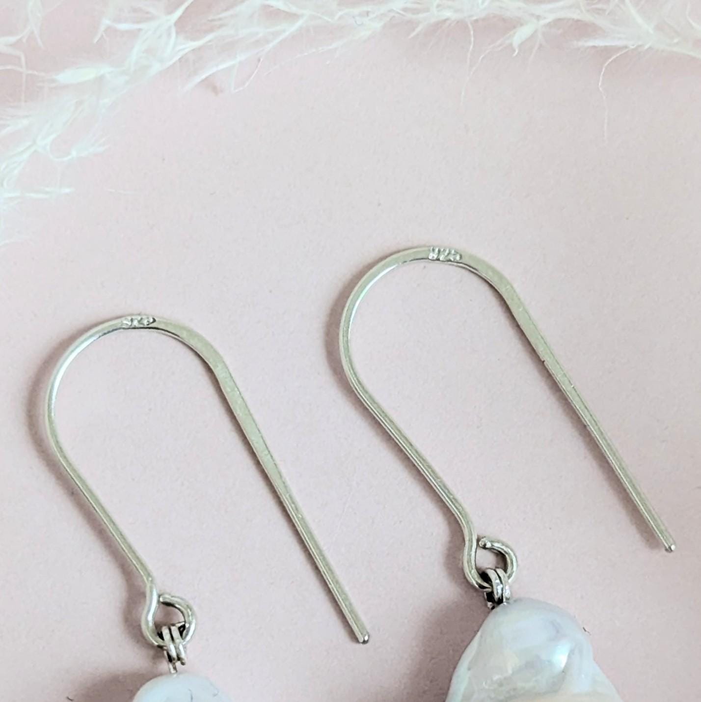 Handcrafted 925 sterling silver genuine large Baroque pearl drop earrings worn on a modern arched sterling silver ear wire