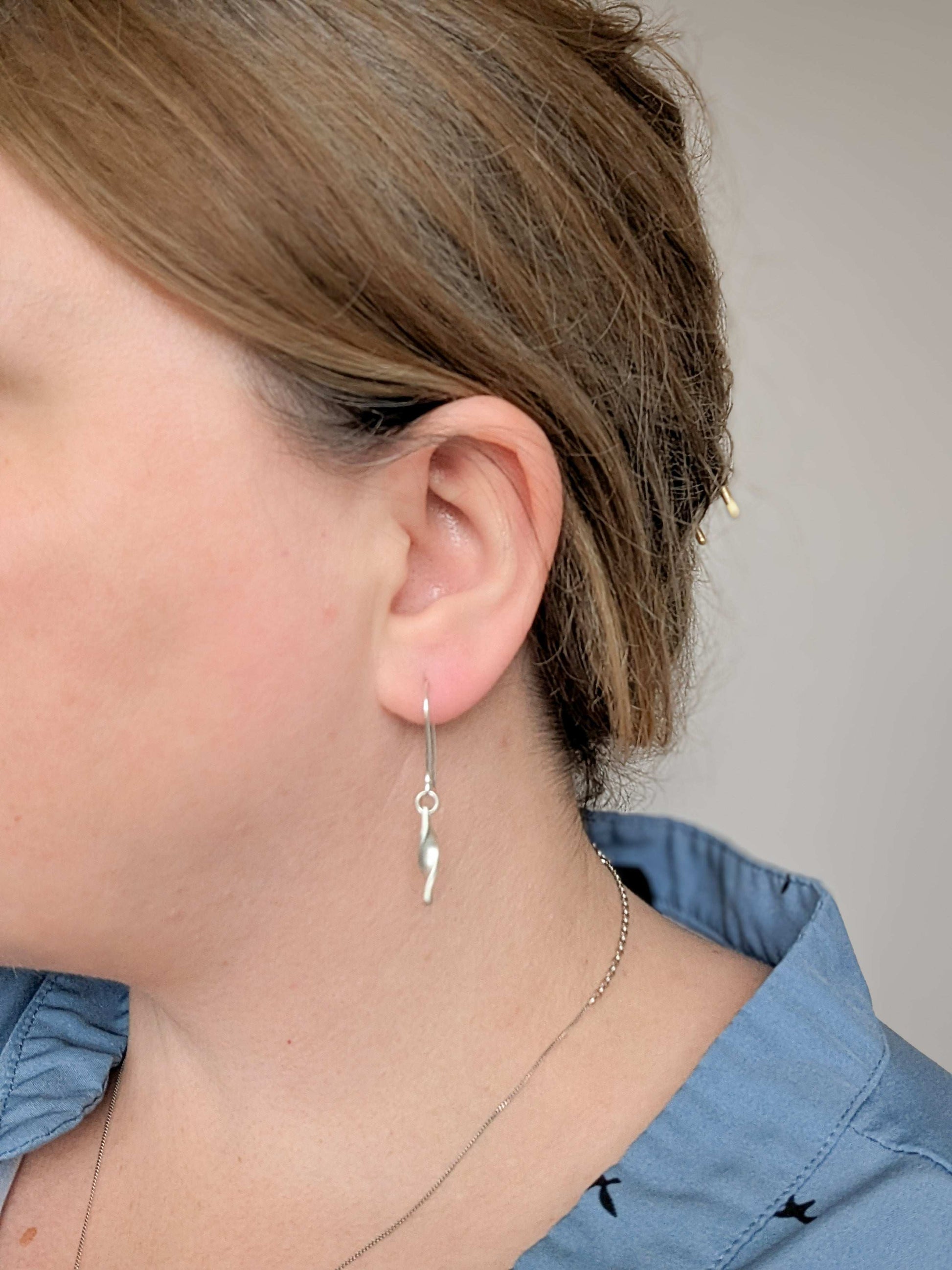 Minimalist satin brushed sterling silver twist drop earrings - worn on earlobe