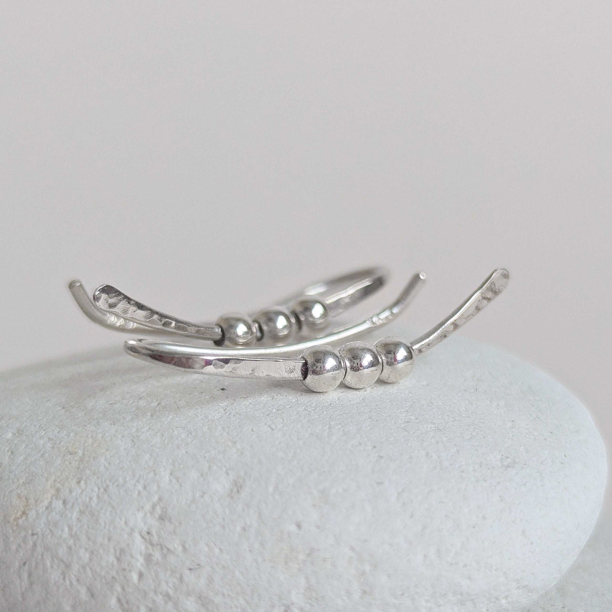 Silver ear climber with bead detailing on a light gray background