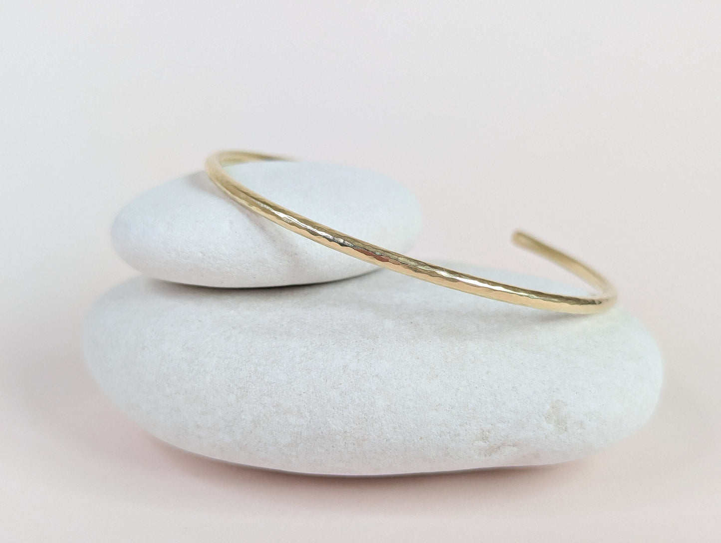 Gold bracelet on a stack of white stones with a light background