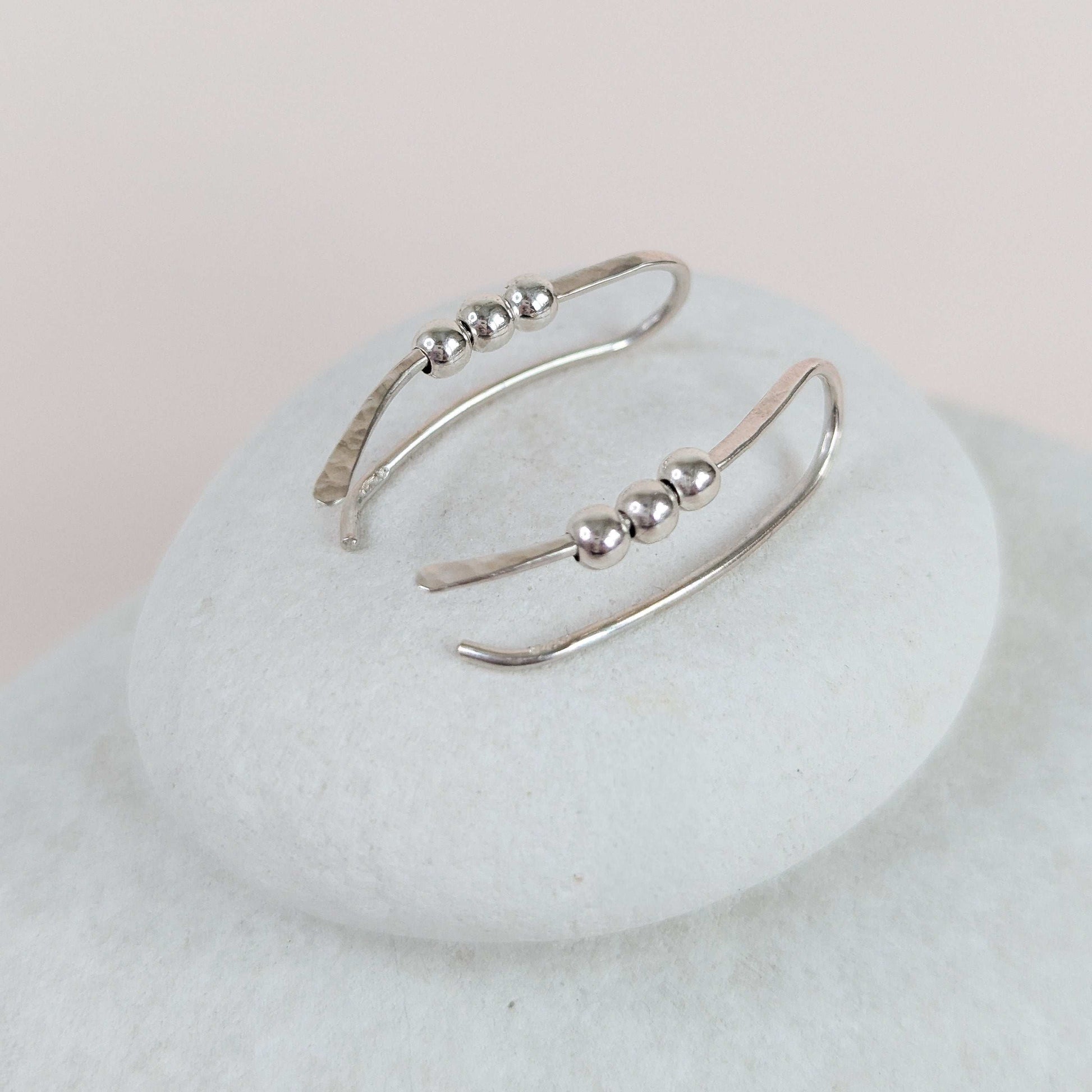 Silver  bead ear climber on a white stone surface