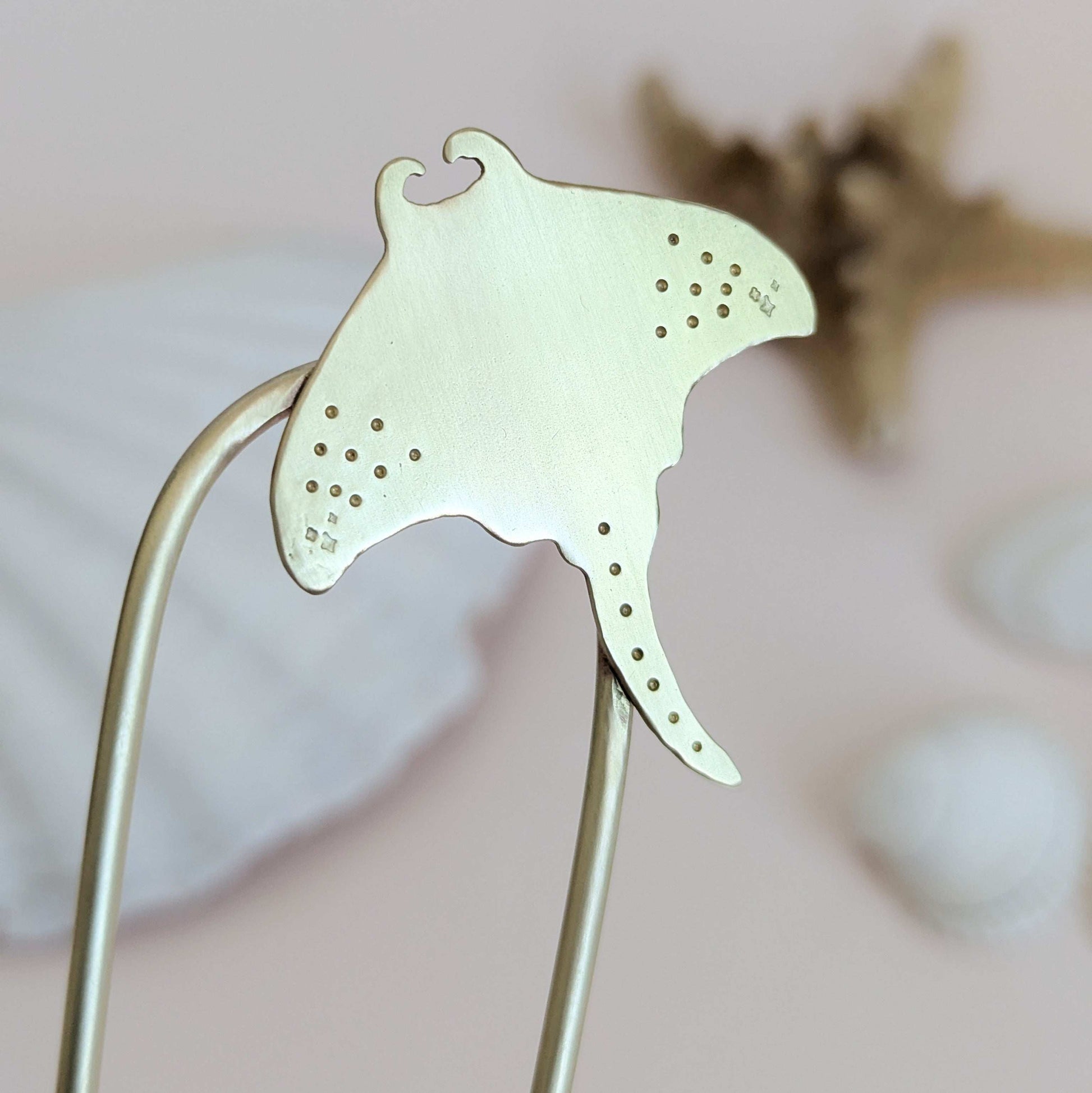 Manta Ray U Pin French hair fork in a brushed brass satin finish - close up of Manta ray secured on the top right of the hair fork with dot and star details on the pectoral fins
