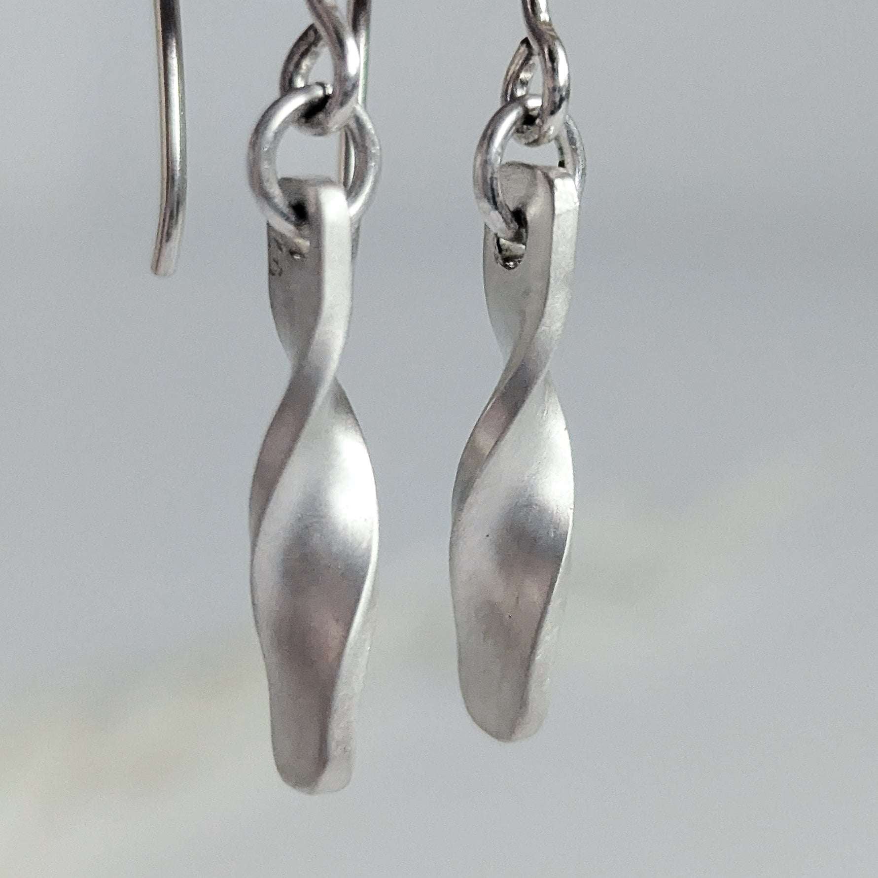 Minimalist satin brushed sterling silver twist drop earrings - macro view