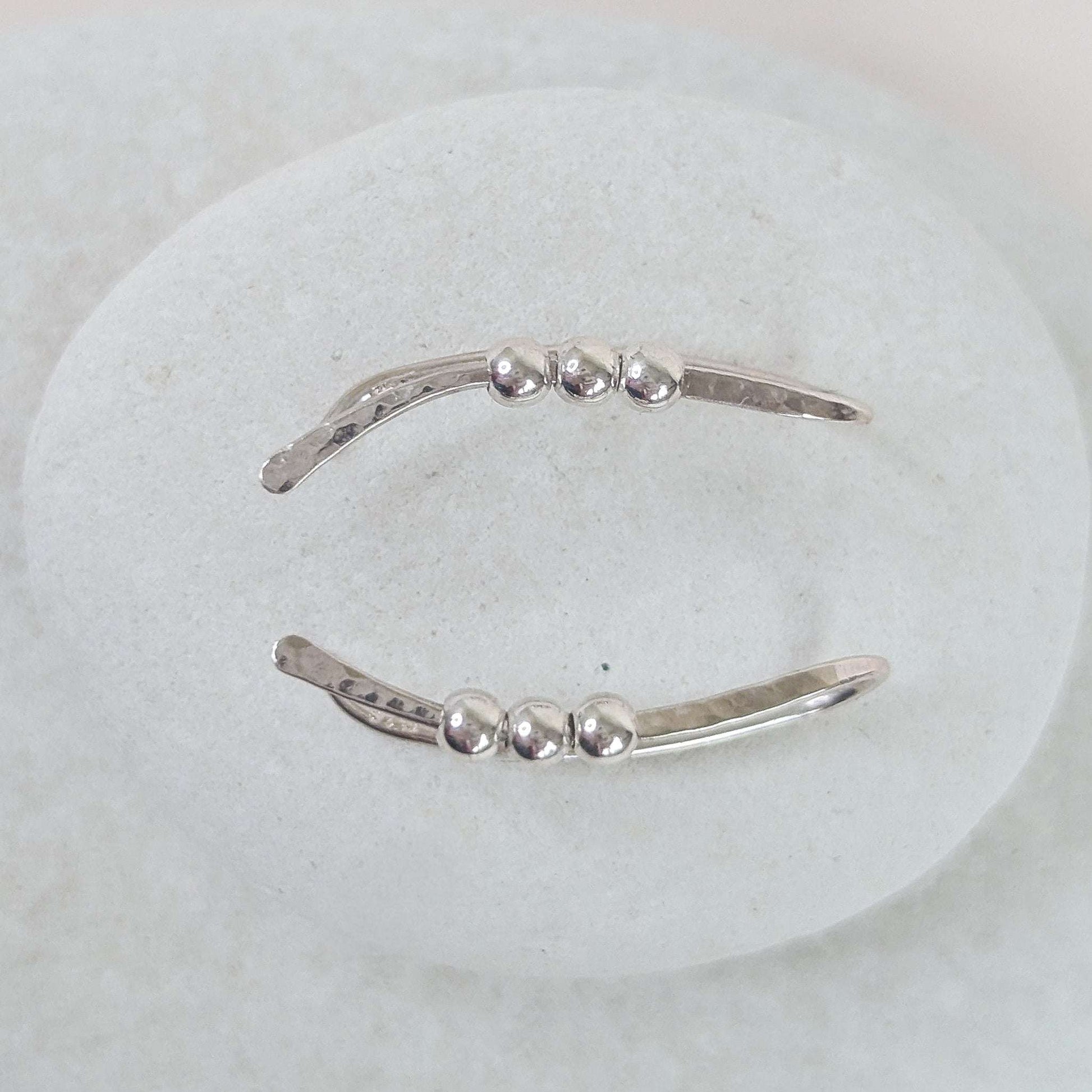 Silver bead ear climber with three small beads on a white background