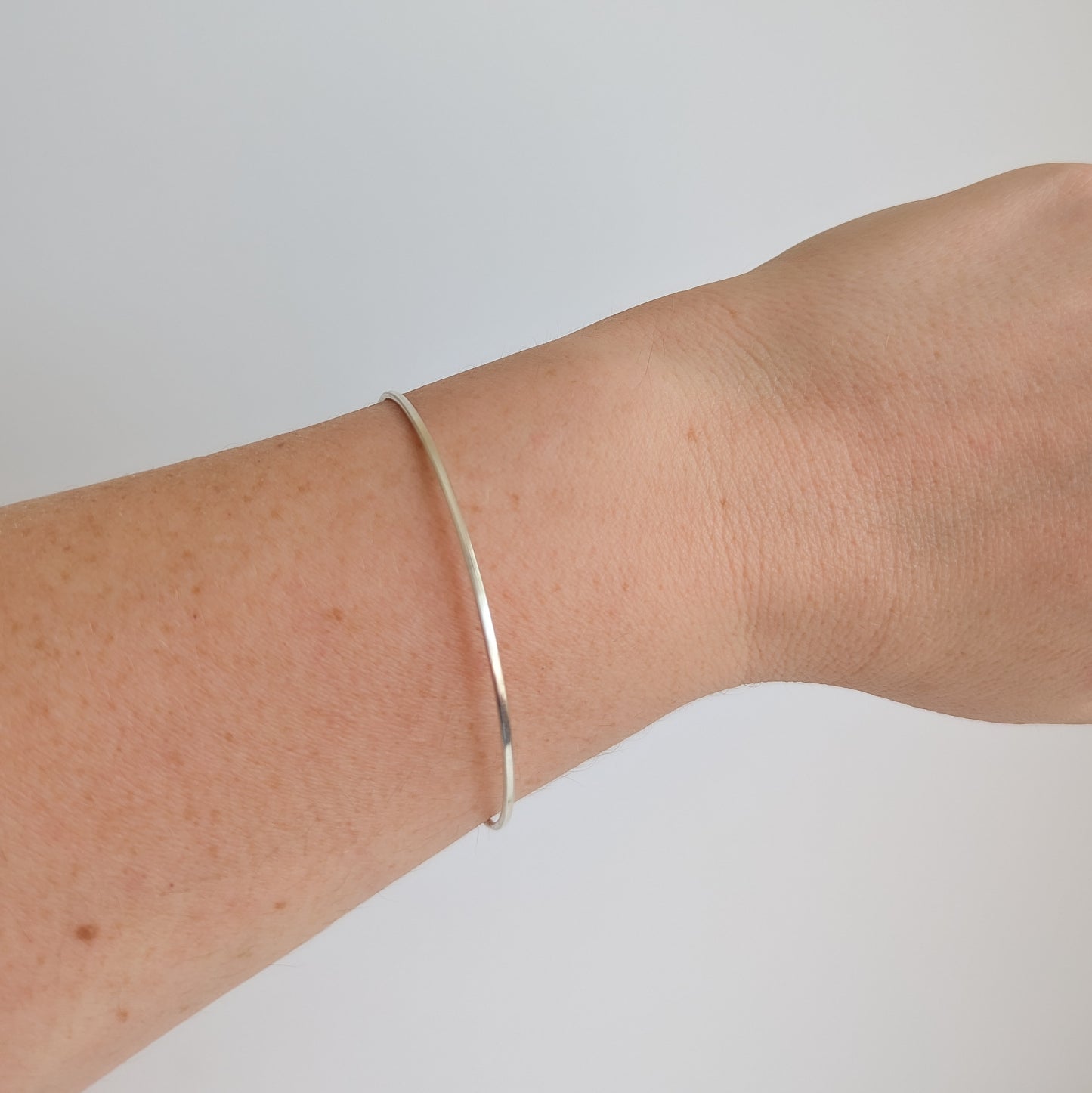 Thin sterling silver dainty cuff bangle with seed pearl bar chain - shows front of cuff being worn on the wrist