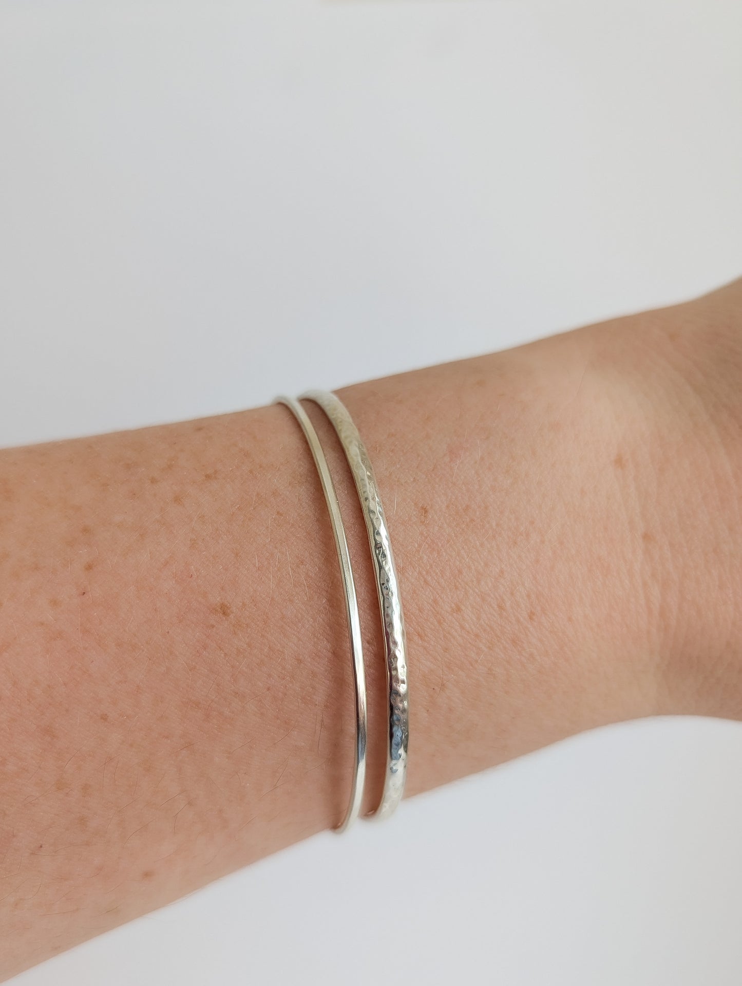Thin sterling silver dainty cuff bangle with seed pearl bar chain - shows front of cuff worn stacked with other bangles