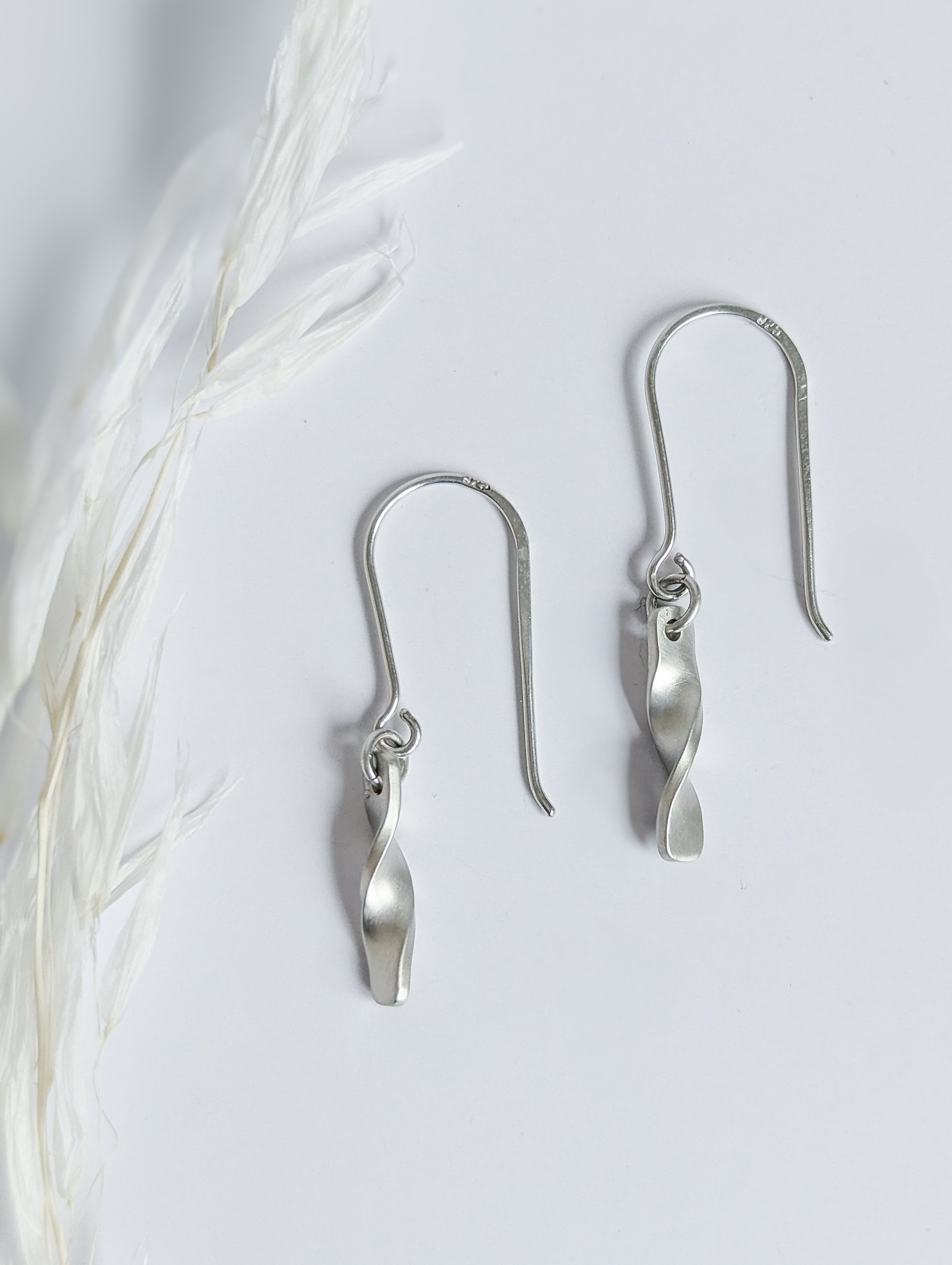 Minimalist satin brushed sterling silver twist drop earrings - top down view