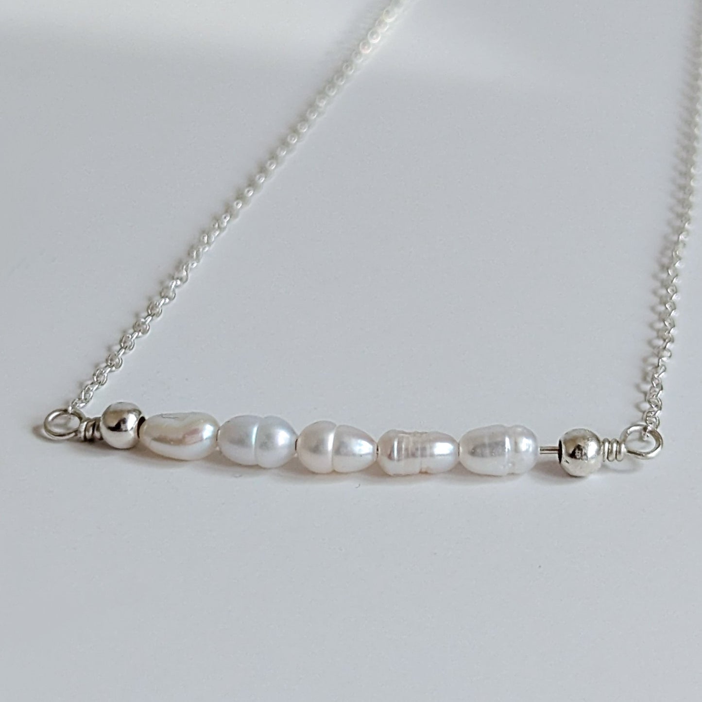 Dainty freshwater seed pearl bar necklace - close up of seed pearl bar containing 5 seed pearls with 2 sterling silver balls on each end