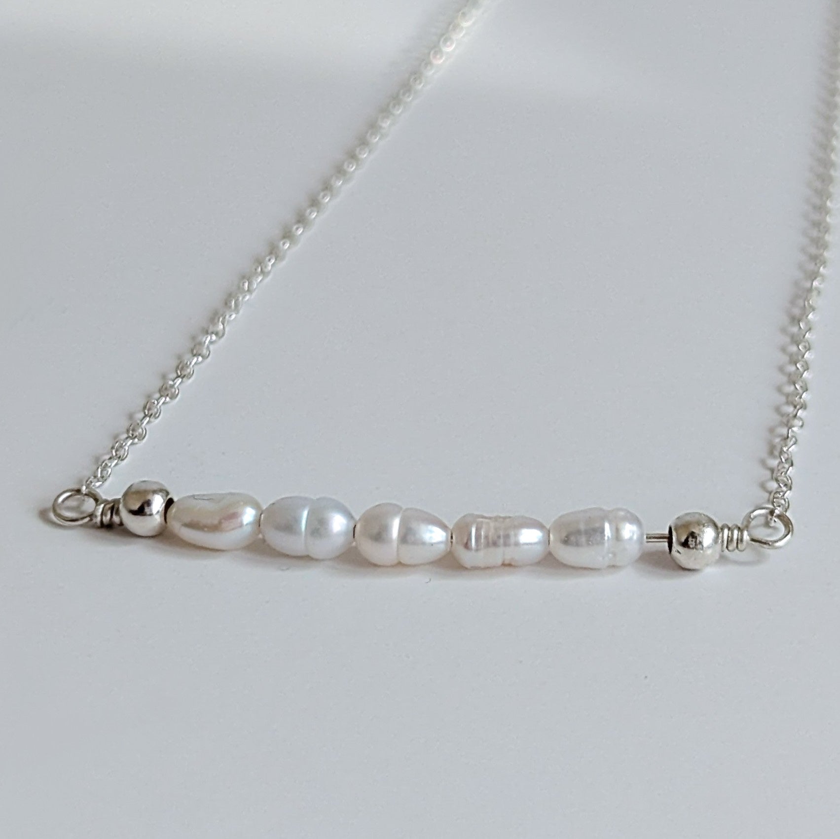 Dainty freshwater seed pearl bar necklace - close up of seed pearl bar containing 5 seed pearls with 2 sterling silver balls on each end