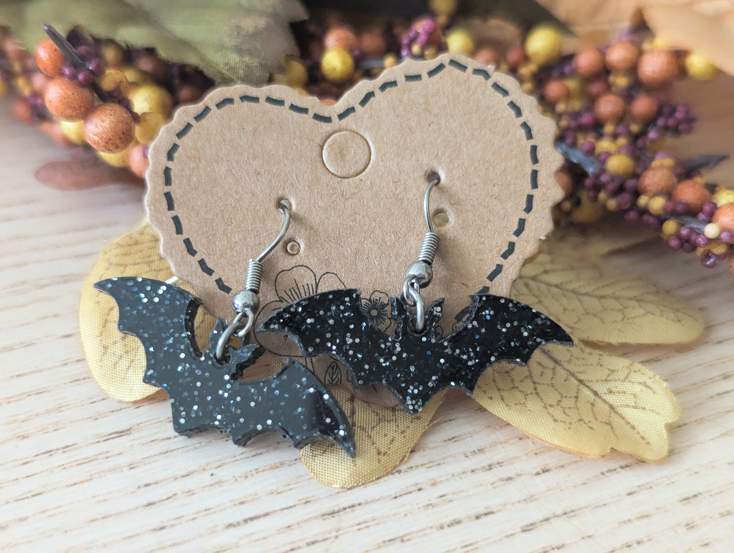 Bat-shaped earrings on a heart-shaped card with a natural background