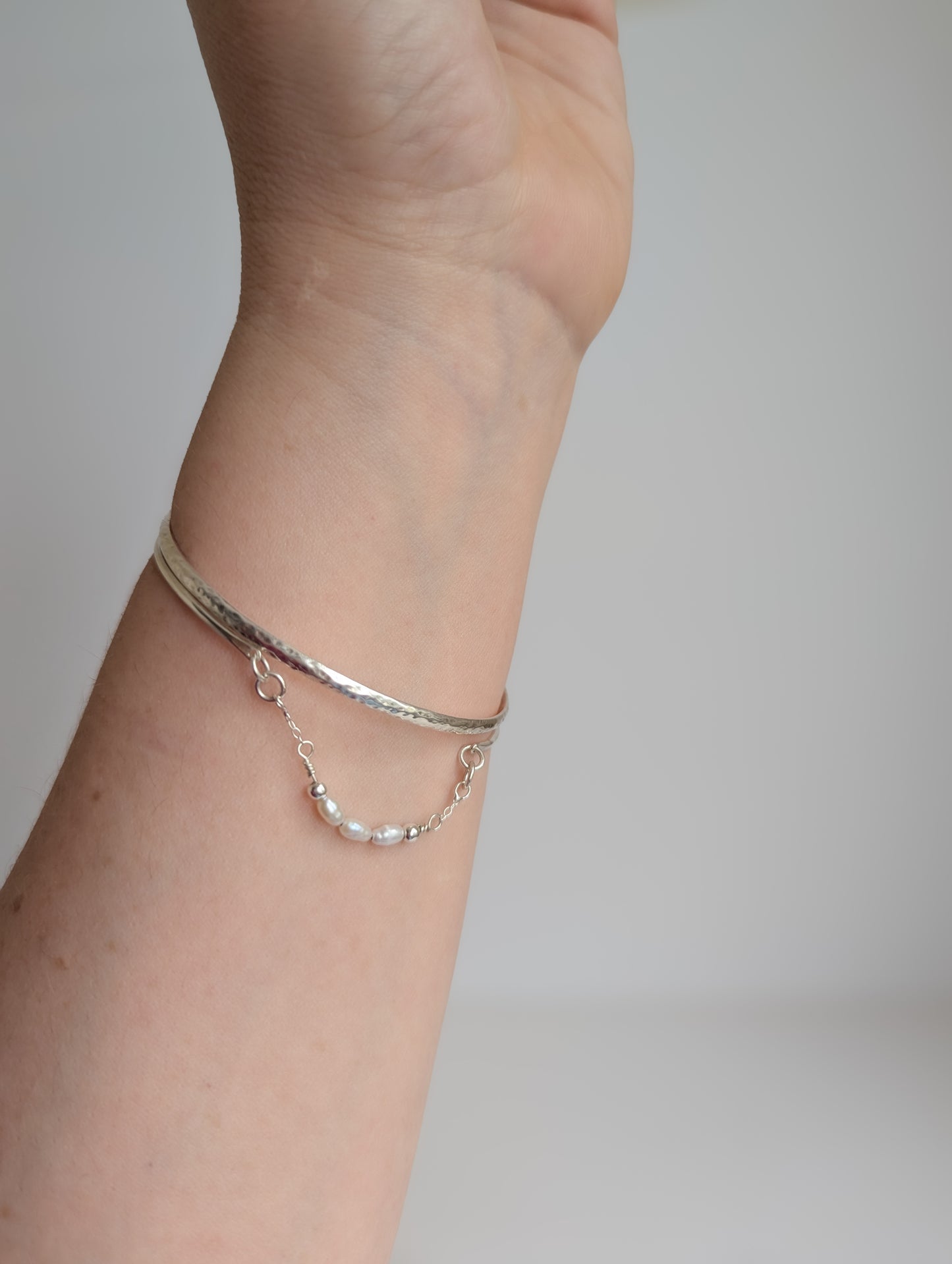 Thin sterling silver dainty cuff bangle with seed pearl bar chain - shows cuff stacked with other bangles