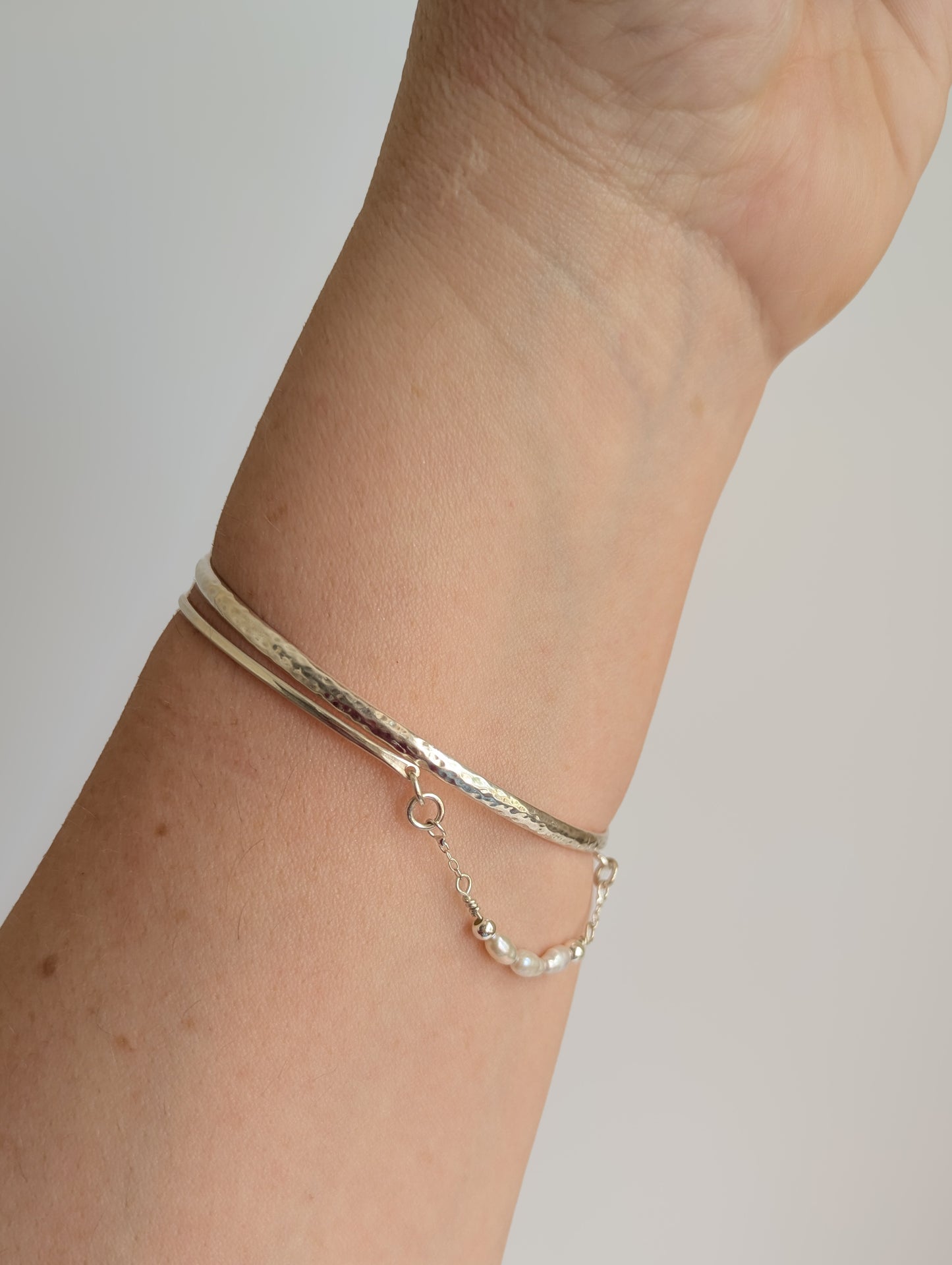 Thin sterling silver dainty cuff bangle with seed pearl bar chain - shows cuff stacked neatly with other bangles