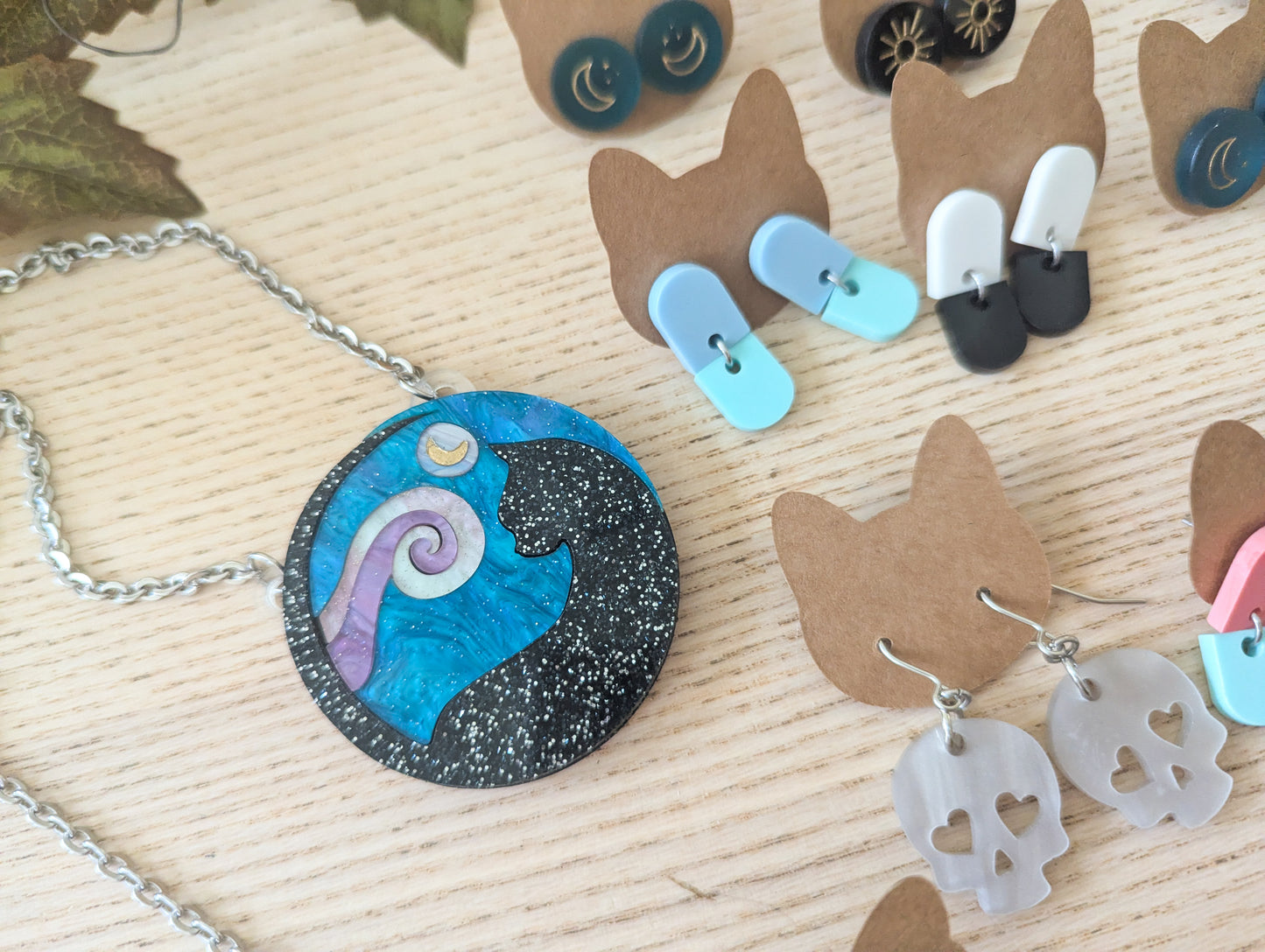 Necklace and earrings on a wooden surface with cardboard display stands.