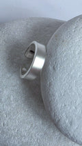 Silver ear cuff on a textured gray surface