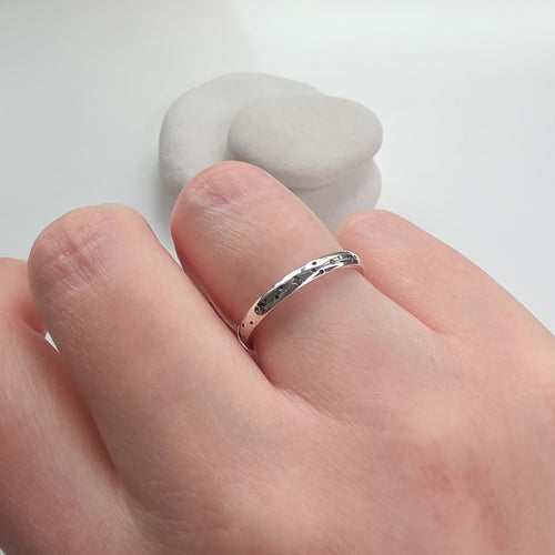 Silver ring on a person's finger with a white background