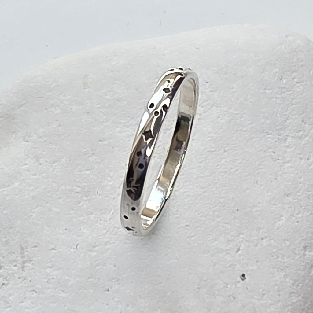 Silver ring with a textured design on a light gray background