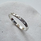 Silver ring with engraved design on a light gray background