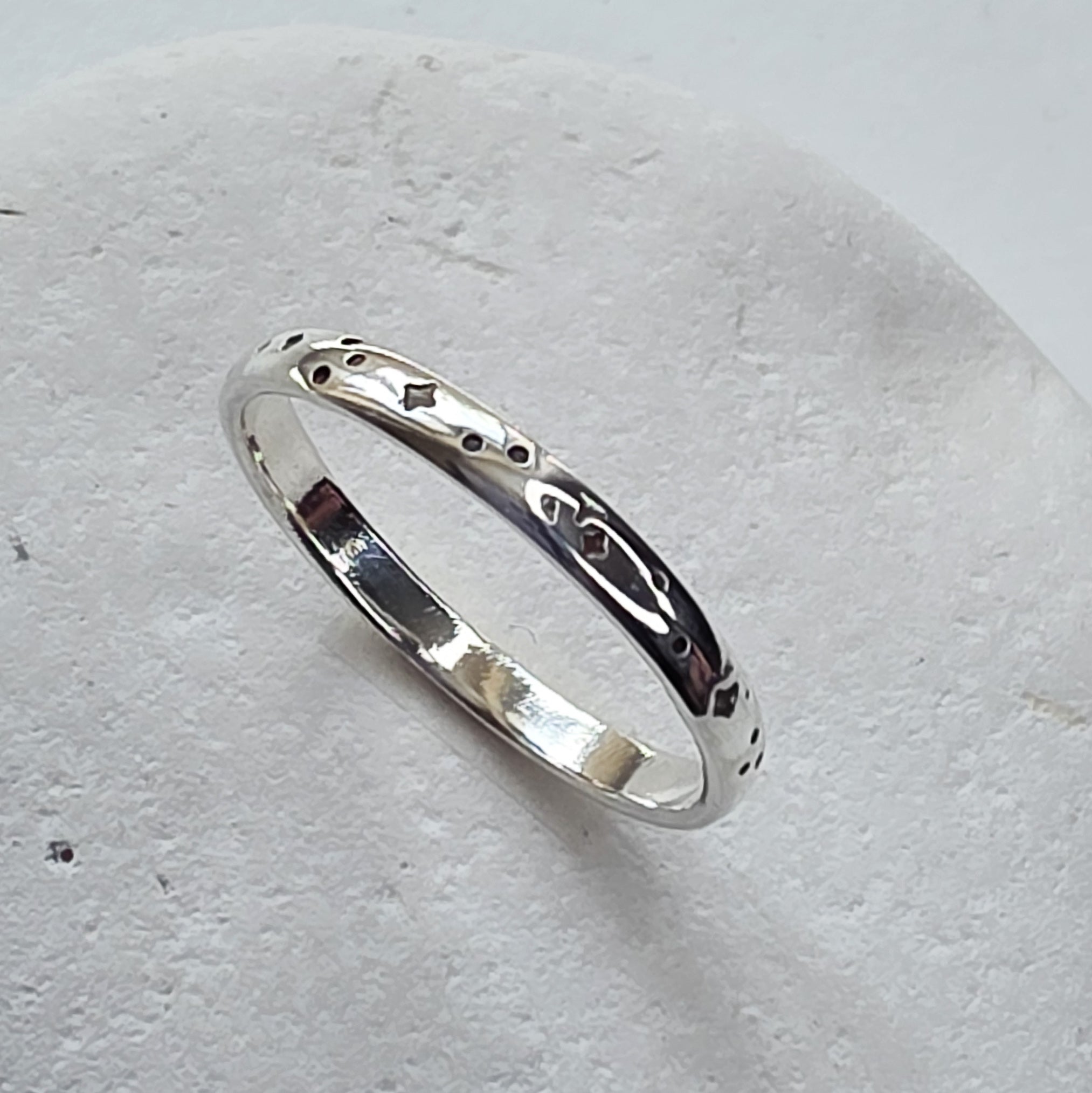 Silver ring with engraved design on a light gray background
