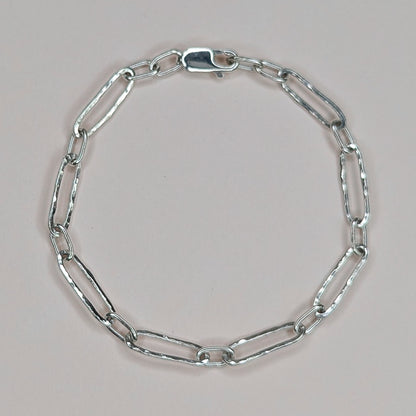 Silver chain bracelet on a light pink background