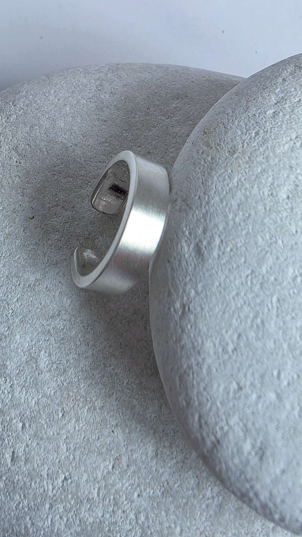 Silver ear cuff on a textured gray surface