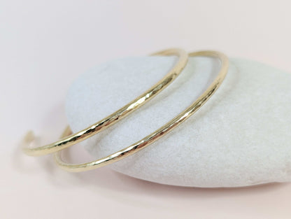 Gold bracelet on a white pebbles with a light pink background