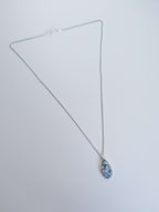 Dendritic snow agate leaf Necklace with a pendant on a light grey surface