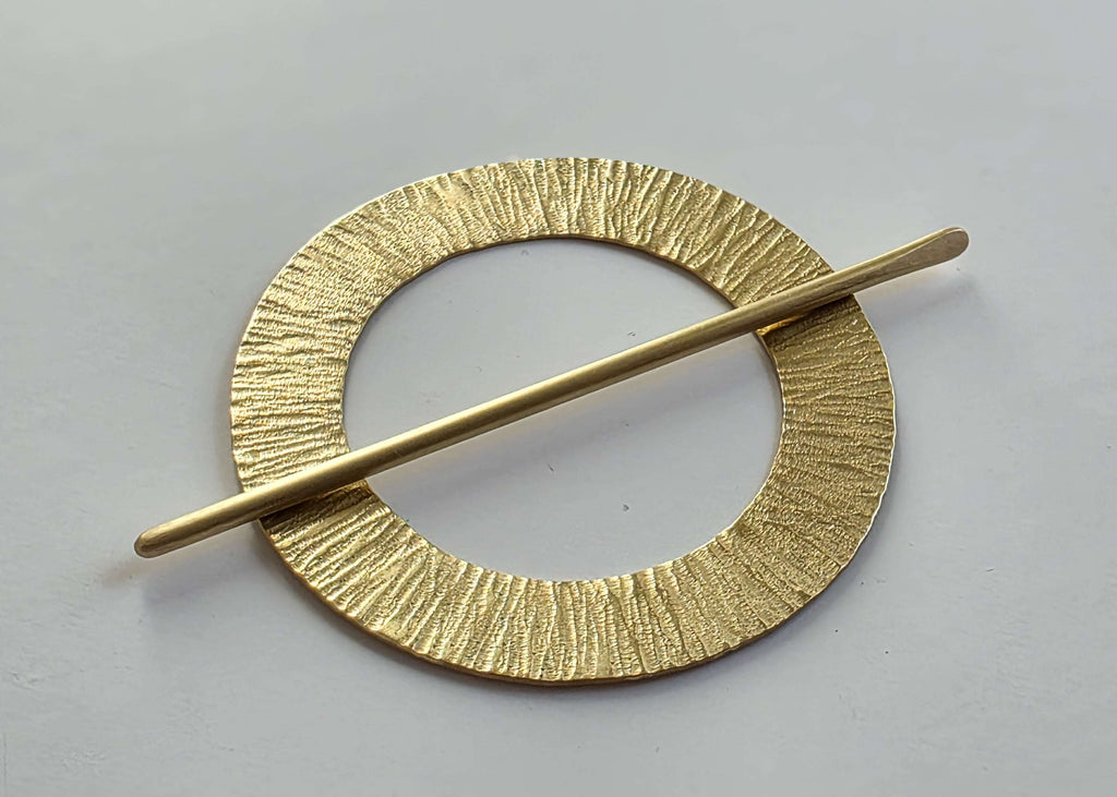 Gold hairpin with circular design on a gray background