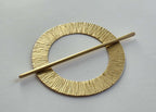 Gold hairpin with circular design on a gray background