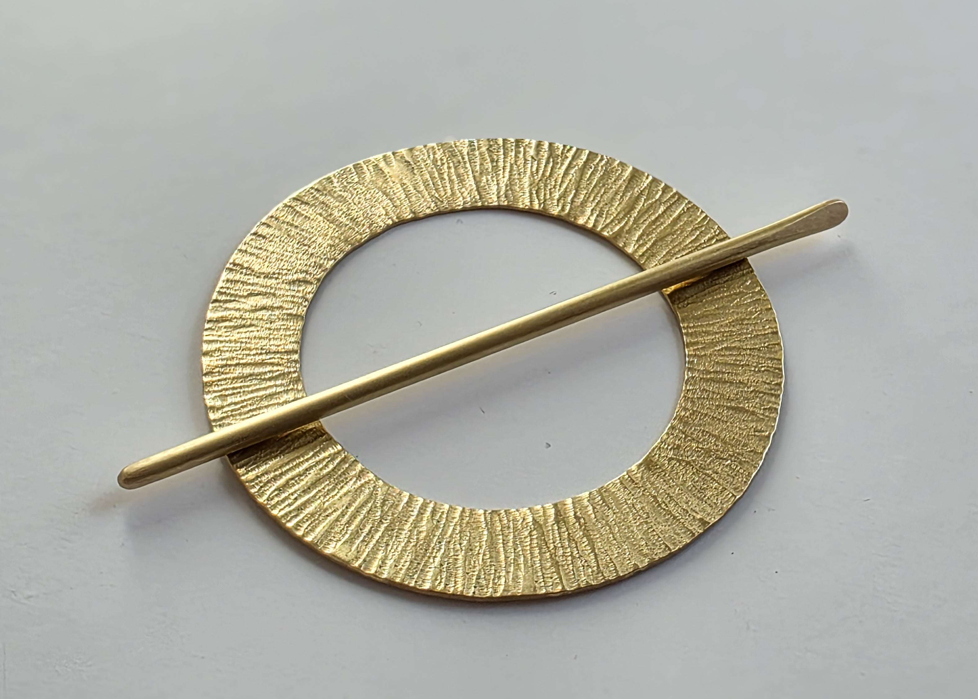 Gold hairpin with circular design on a gray background