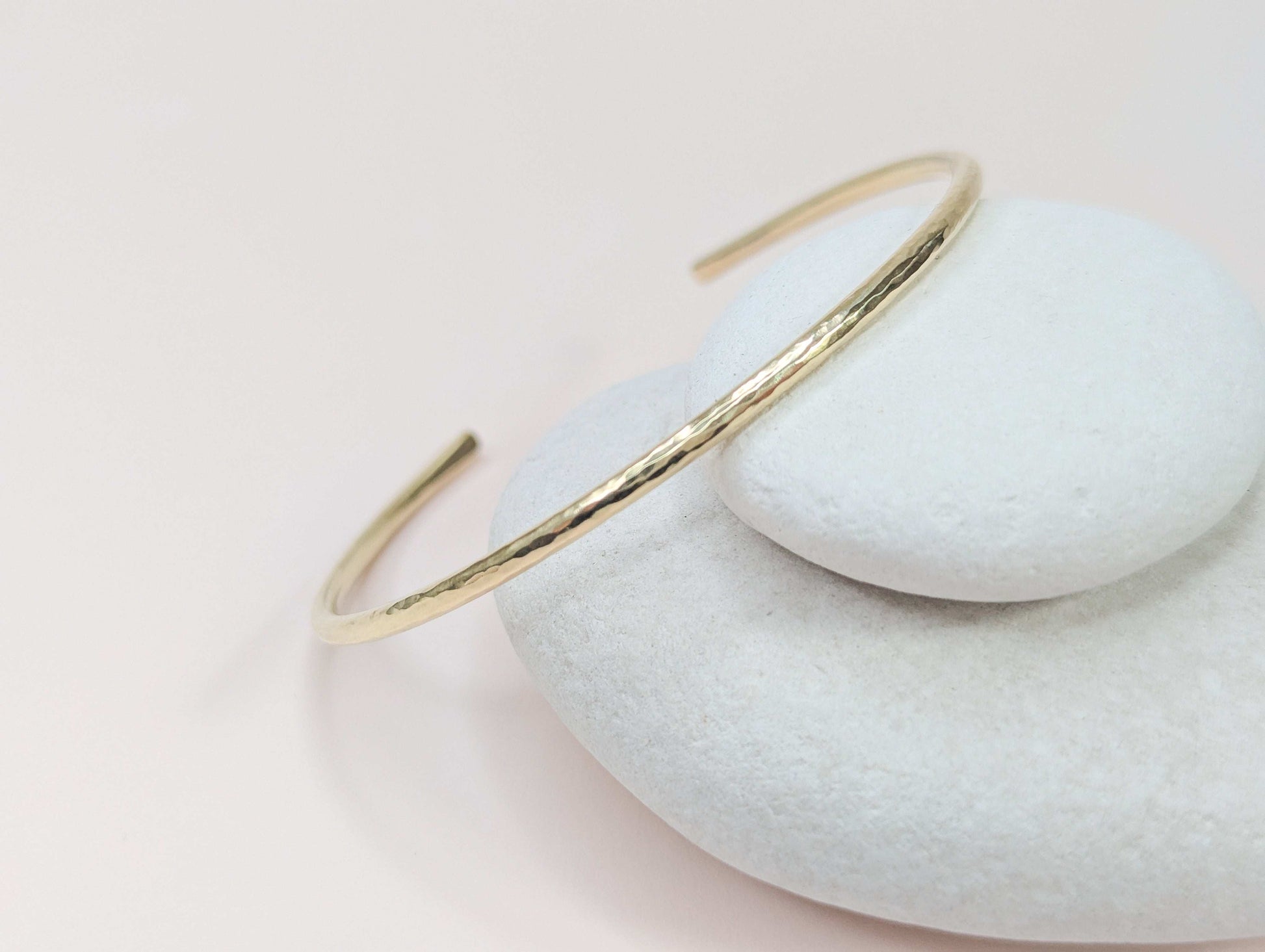 Gold bangle on a light pink background