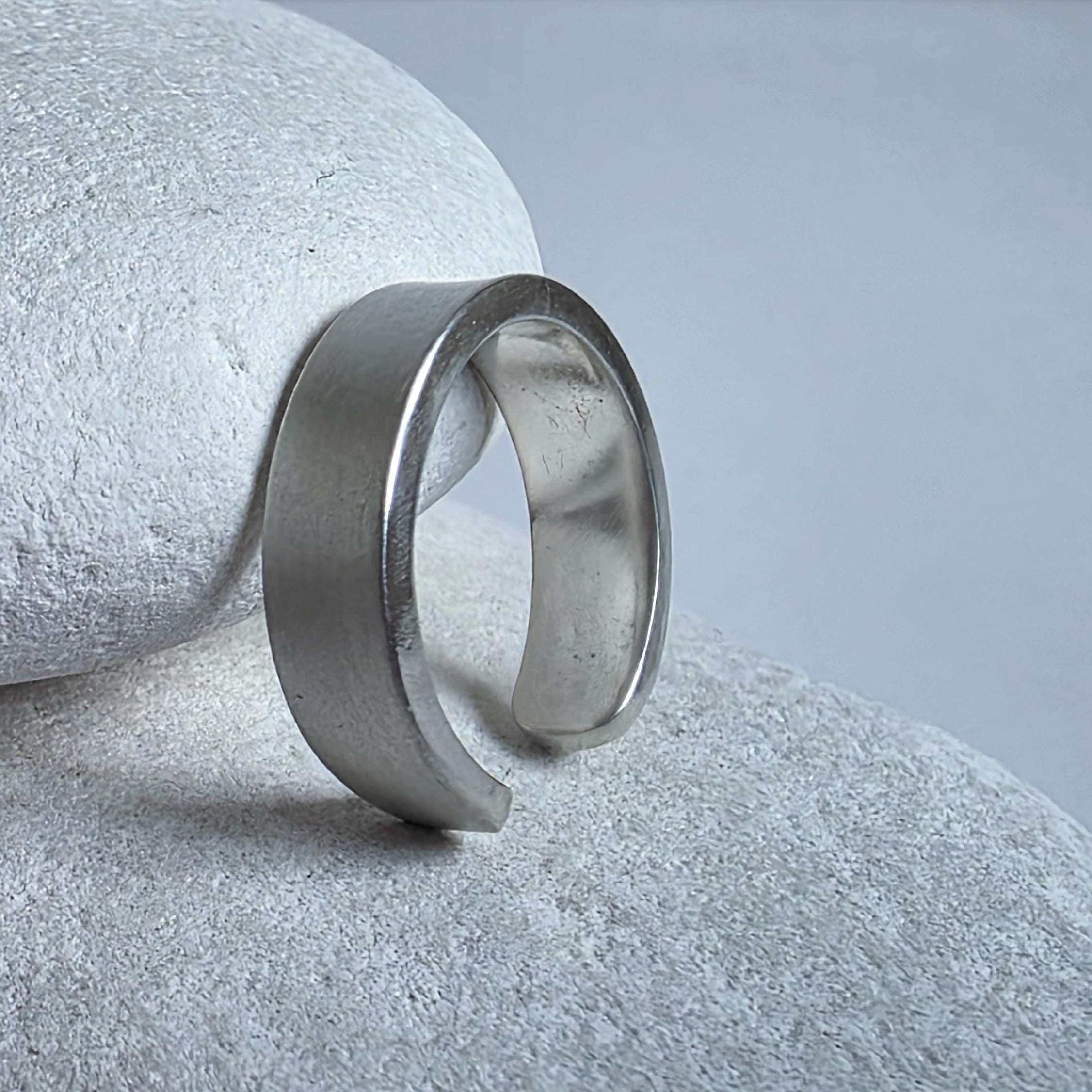 Silver ear cuff on a textured stone surface with a neutral background