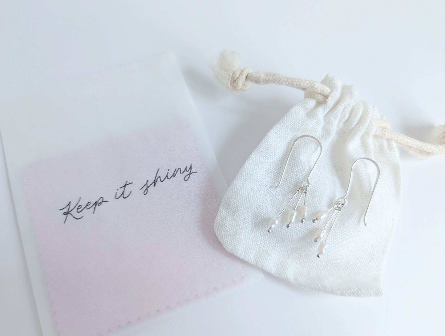 Dainty freshwater seed pearl dangle cascade drop earrings in Sterling silver - shows packaging including white cotton drawstring bag and polishing cloths 