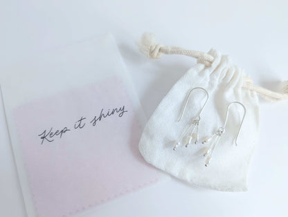 Dainty freshwater seed pearl dangle cascade drop earrings in Sterling silver - shows packaging including white cotton drawstring bag and polishing cloths 