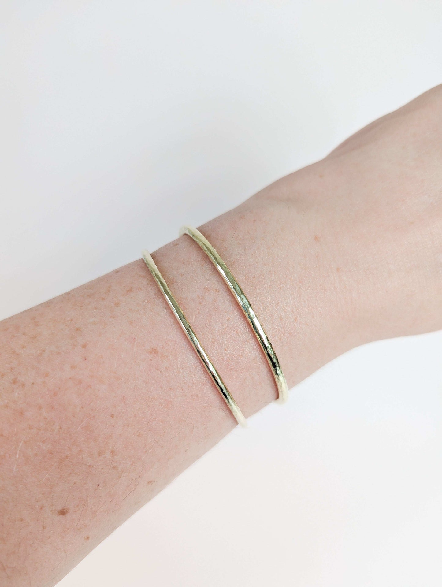 Gold bracelet on a wrist against a white background