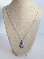 Dendritic snow agate leaf Necklace on a mannequin bust against a plain background