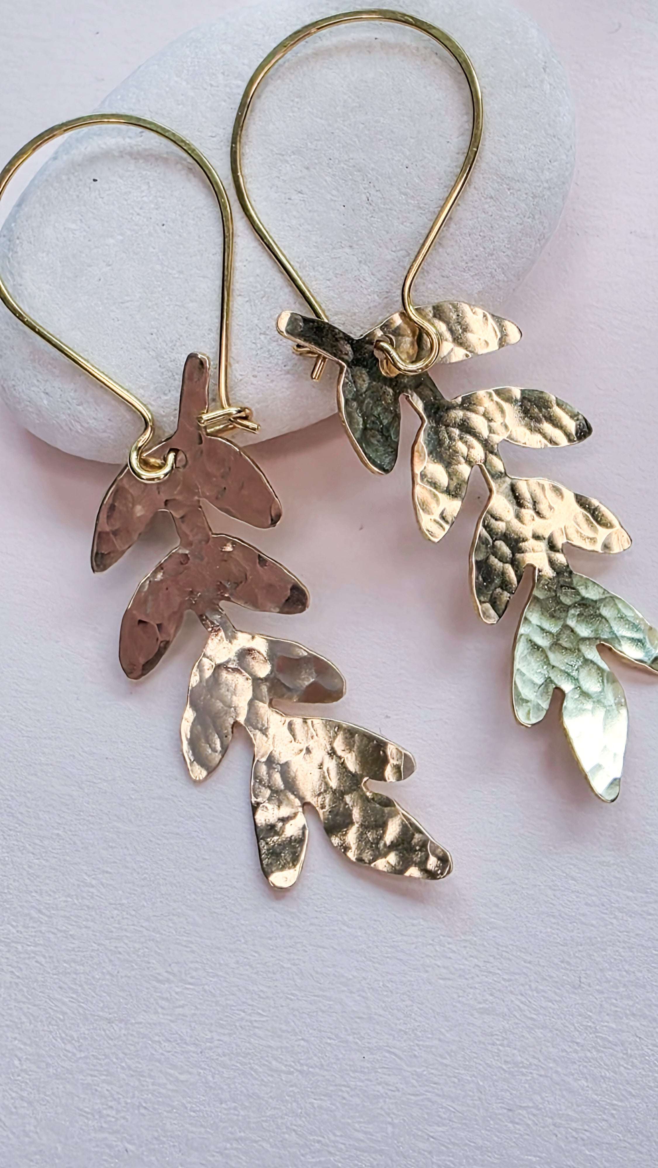 Pair of gold leaf-shaped earrings on a light background