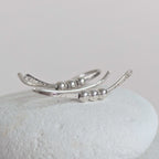 Silver ear climber with bead detailing on a light gray background