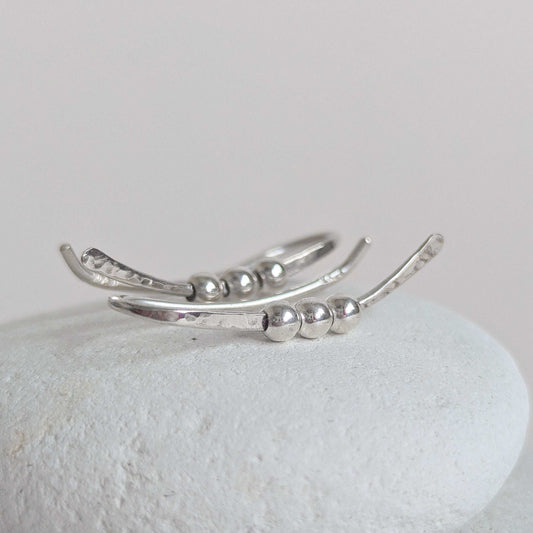 Silver ear climber with bead detailing on a light gray background