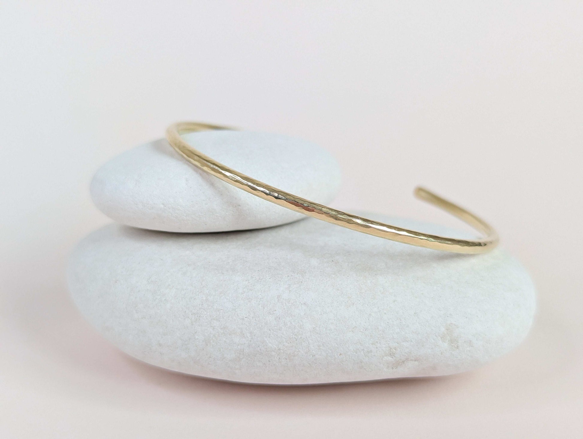 Gold bracelet on a stack of white stones with a light background