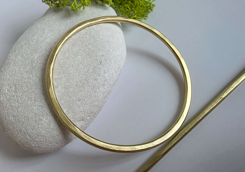 Gold brass hair barrette  on a textured stone surface with green moss