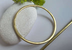 Gold brass hair barrette  on a textured stone surface with green moss
