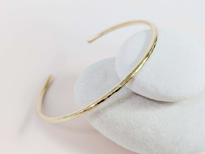 Gold bracelet on a white stone surface