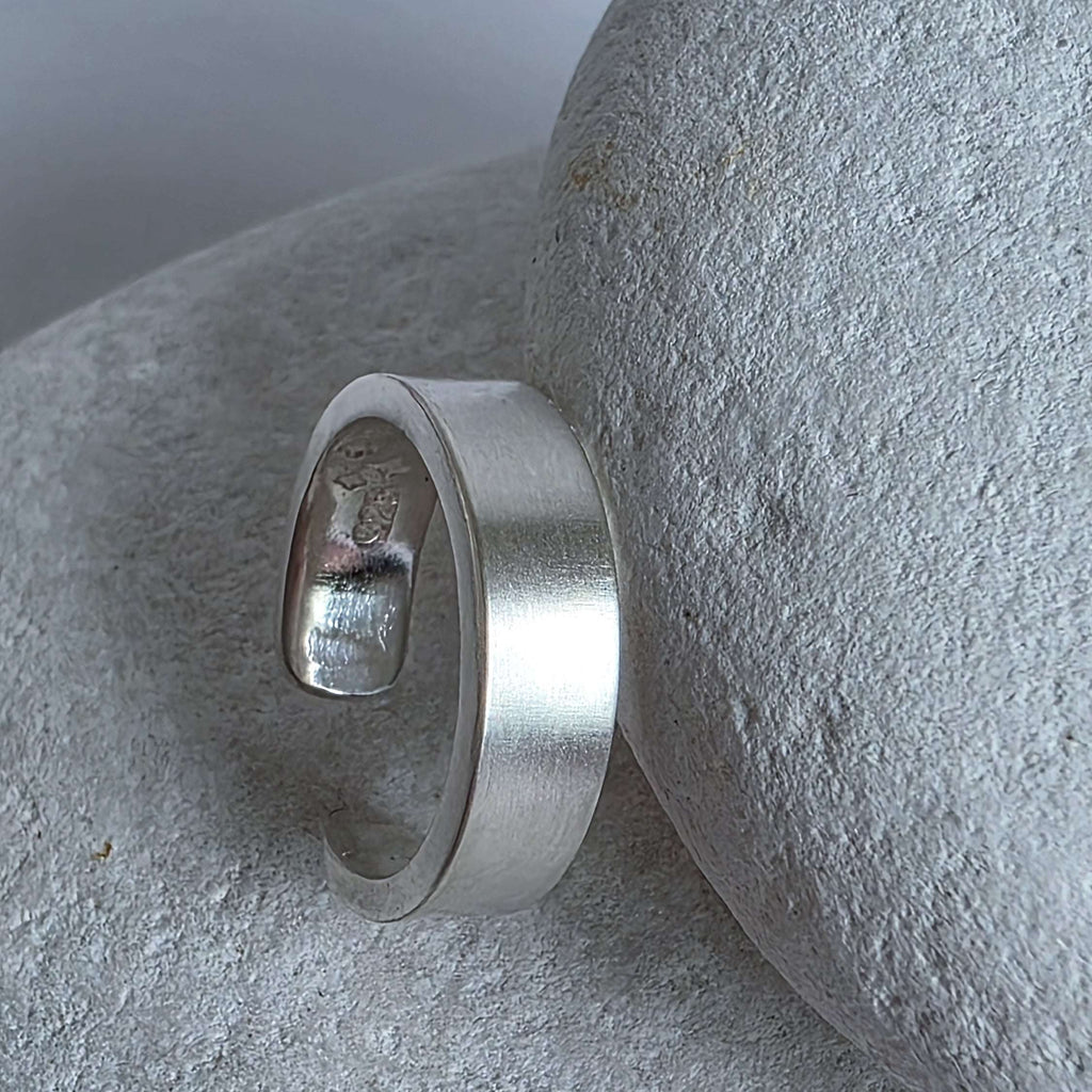 Silver ear cuff on a textured stone surface