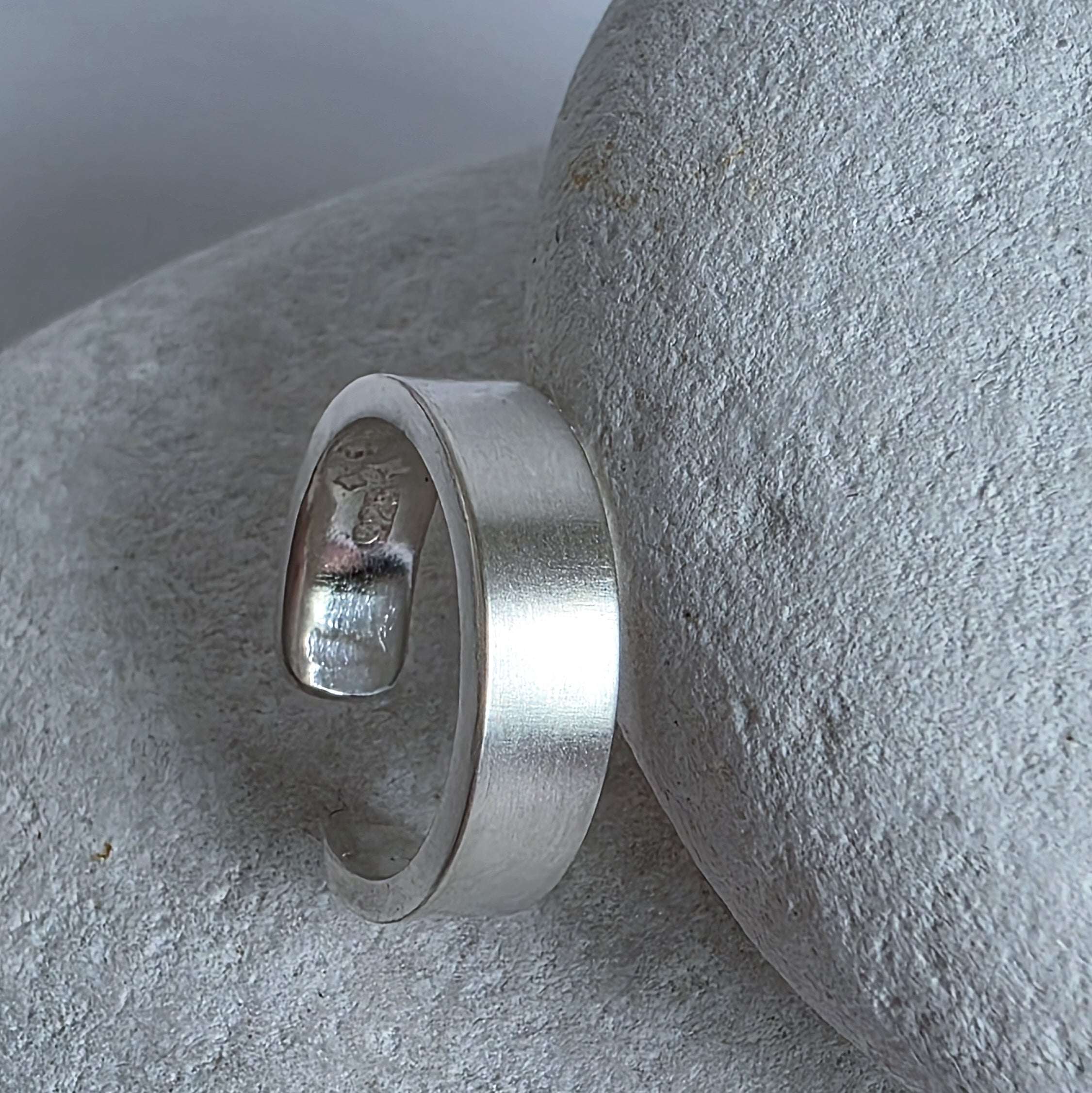 Silver ear cuff on a textured stone surface